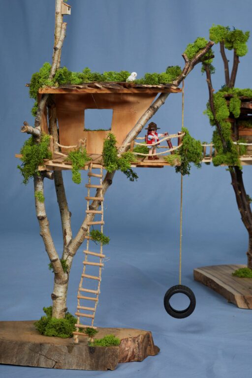 Auf dem Bild ist ein kleines Baumhaus zu sehen mit einer Playmobilfigur.